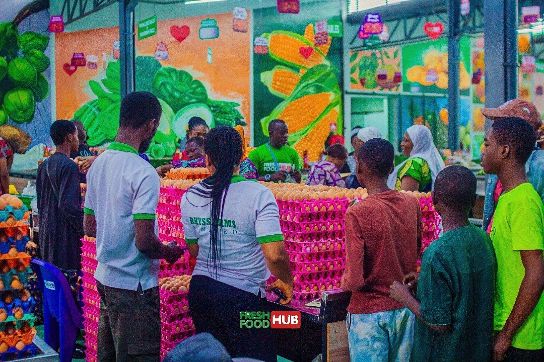 Shoppers at the Rhyss Farms egg stand in front of a painted market mural.